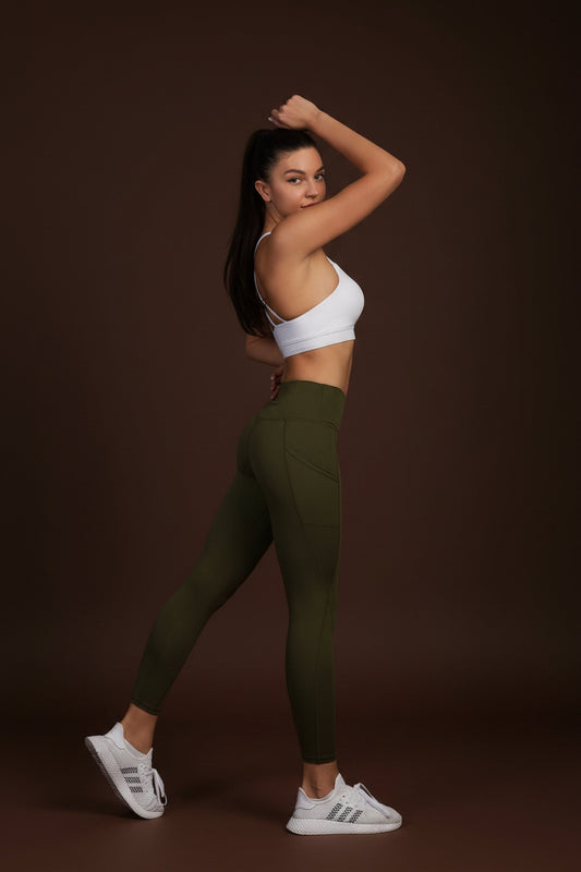 Woman wearing olive green yoga leggings, side pose